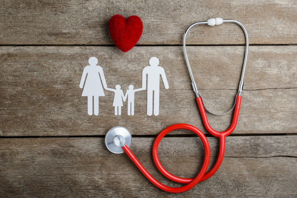 Red heart, stethoscope and paper chain family on wooden table